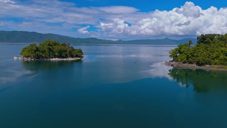 drone flying forwards over lake mainit betweens island and coastline in the philippines