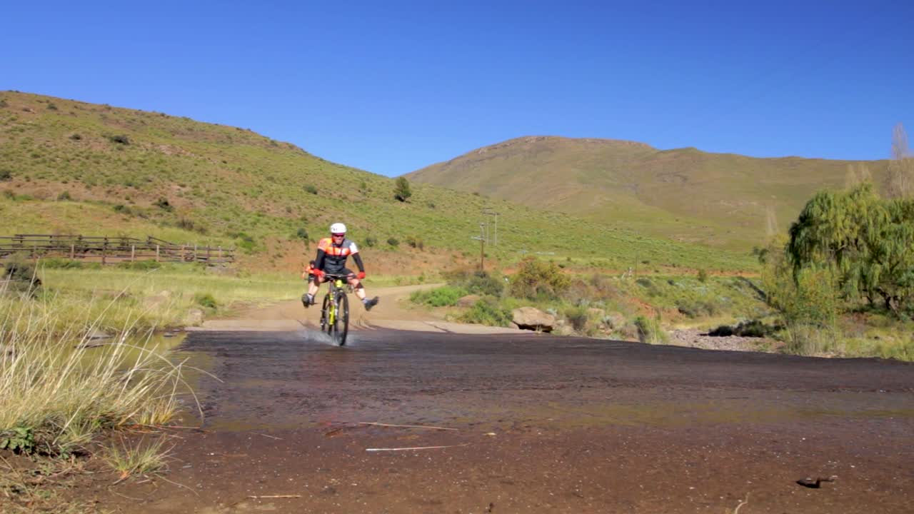 Mountain bikers riding through a stream of shallow water