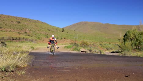 mountain bikers riding through a stream of shallow water