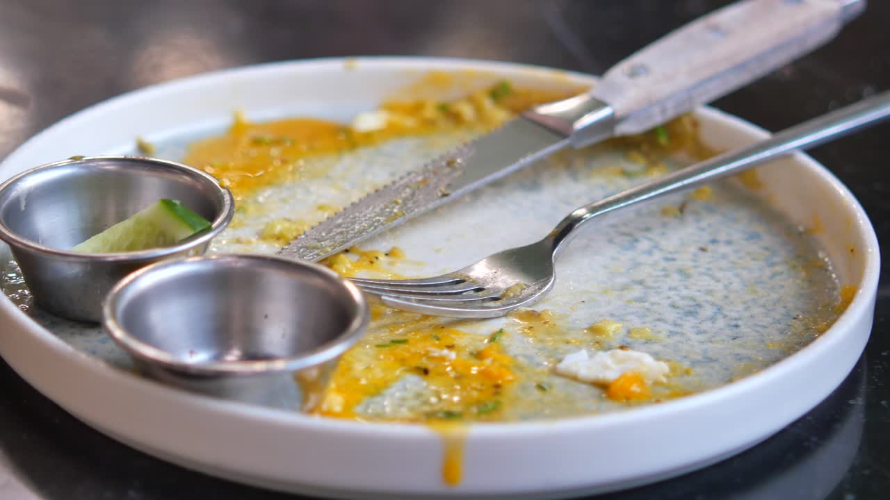 An empty plate with leftover food and cutlery
