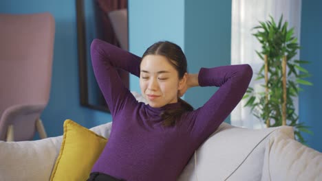 asian woman sitting alone in the living room, laughing in a good mood.