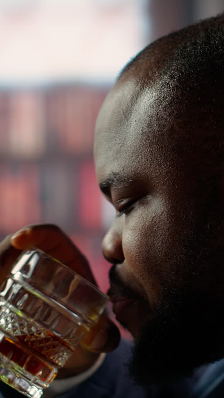 Man Sips Whiskey from a Crystal Glass in a Dimly Lit Room