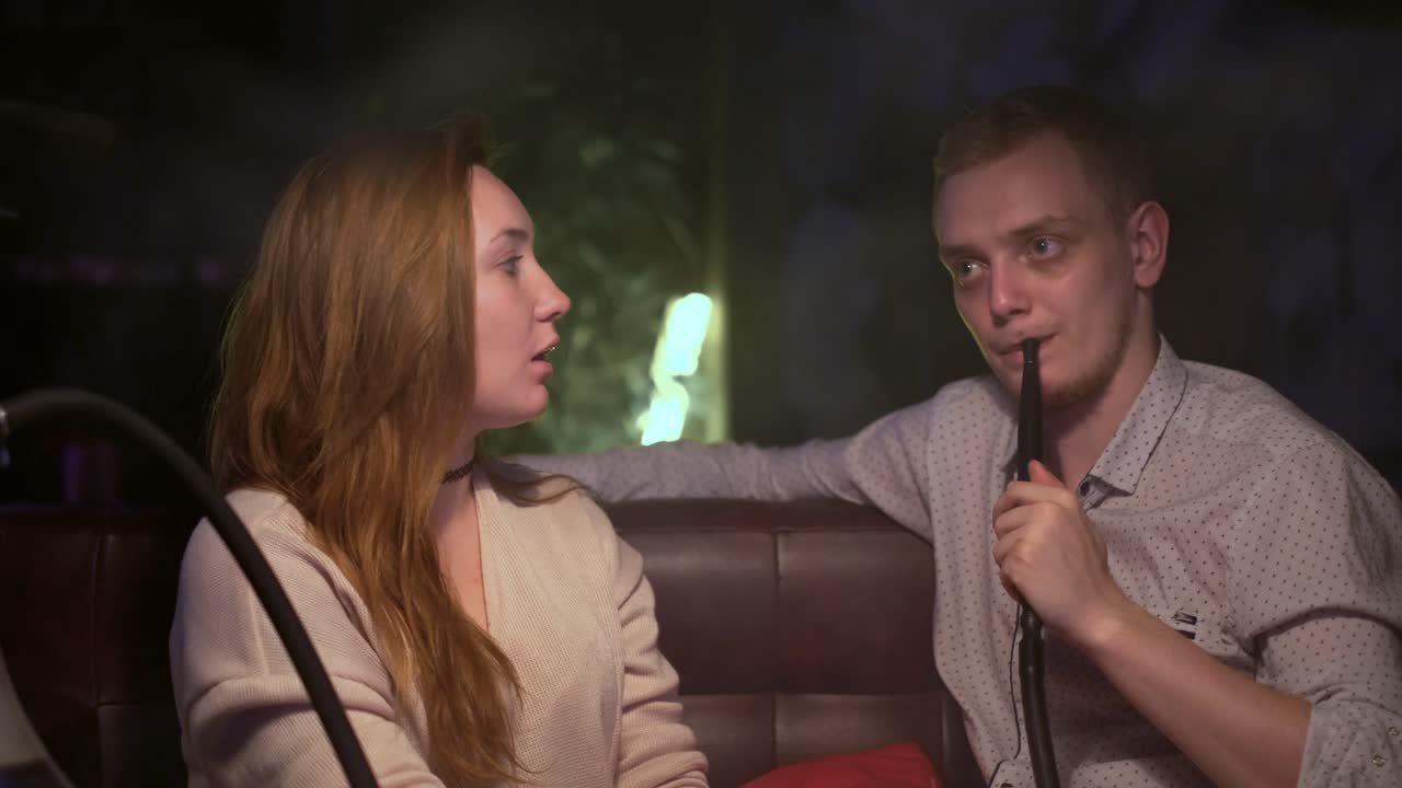 한 커플 이 라운지 에서 호카 를 즐기고 있다