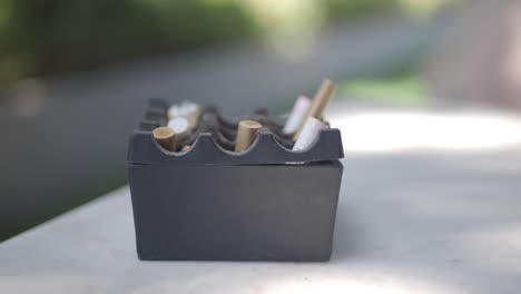 cenicero usado con colillas de cigarrillo