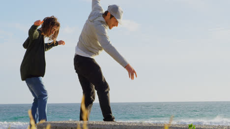 side view of young caucasian men practicing skateboard trick on the pavement at beach 4k