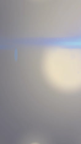 animation of flaring light beam moving over bokeh white light spots on grey background