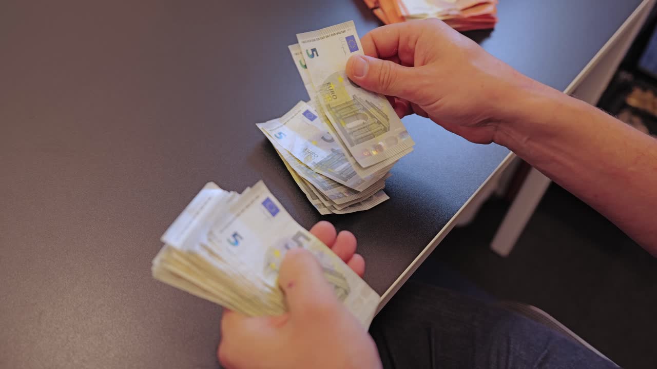 Banconote in euro in mano al rallentatore dall'alto verso il basso con luce diurna mista