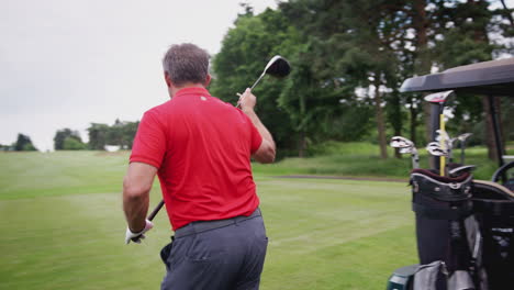 Reifer-Männlicher-Golfspieler,-Der-Den-Schläger-Aus-Der-Tasche-Auf-Dem-Buggy-Auswählt,-Bevor-Er-Den-Golfball-Auf-Den-Abschlag-Legt