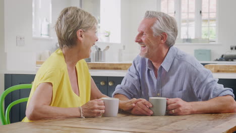 Una-Pareja-De-Jubilados-Sentados-Alrededor-De-Una-Mesa-En-Casa-Tomando-Un-Café-Juntos-Por-La-Mañana