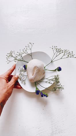 white plate arrangement with flowers and rock