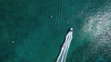 Tiro-De-Drone-De-Adrenalina-Deporte-Acuático-Anillo-De-Tubo-Remolcable-Con-Acción-De-Lancha-Rápida-En-Mar-En-Calma