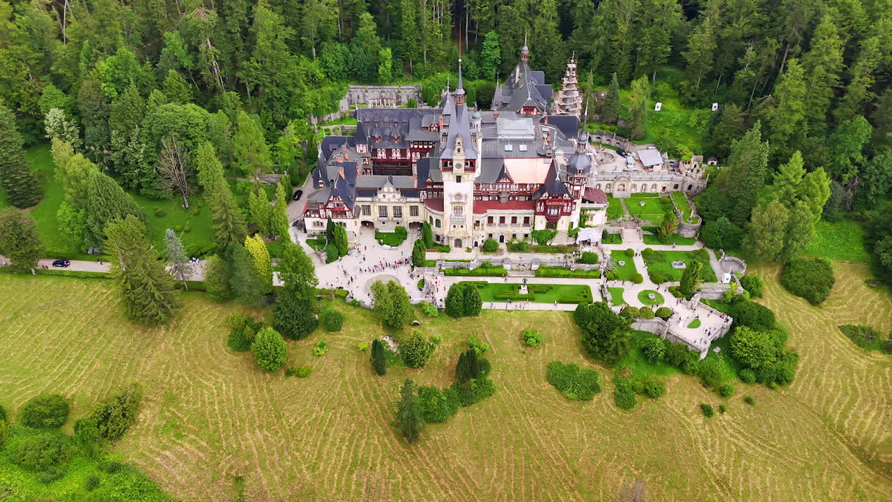 Fantastisk arkitektur av Peleș slott, Prahova fylke, Romania i Karpatene. Filmopptak med drone som nærmer seg landemerket omgitt av skog