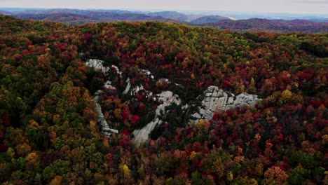 Weathered-granite-rock-shroud-fall-foliage-pine-mountains,-southeastern-Kentucky,-AERIAL-REVERSE-DOLLY