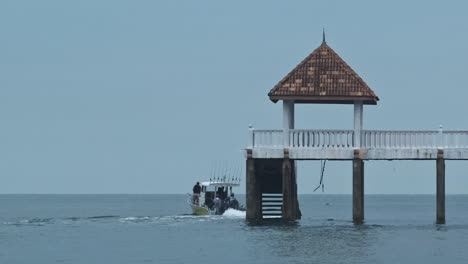 fishing boat leaving pier during cloudy day early in the morning