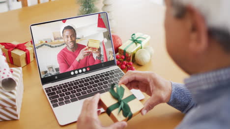 biracial man with gift having laptop video call with happy african american man