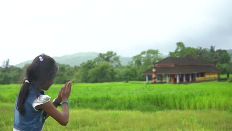 little girl praying near temple farm malvan maharashtra back shot