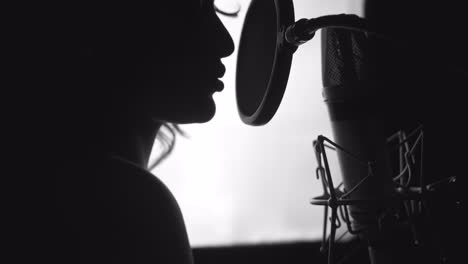 black and white. woman singing in the recording studio. profile of a woman with a beautiful face and lips.