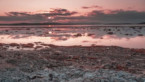 Roter-Sonnenuntergangshimmel-Und-Vorbeiziehende-Dunkle-Wolken,-Die-Sich-Im-Spiegelglatten-Fjord-Spiegeln