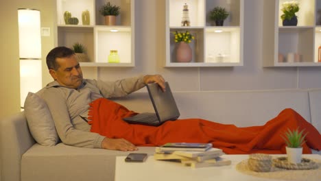 man using laptop while lying down closes laptop nervously.