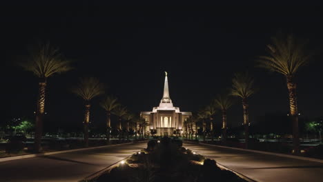 templo mormón de la iglesia lds en la noche en gilbert, arizona desde la distancia con un camino bordeado de palmeras que conduce al templo lds