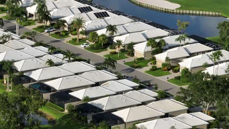 Similar luxury houses with solar panels on palm trees at golf course in Bradenton, Florida. Sunset time in summer. Aerial zoom slide shot. Well-kept front yards of properties