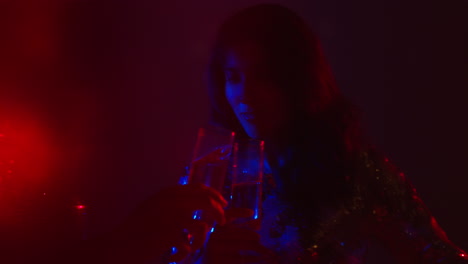 close up of two women in nightclub bar or disco dancing and drinking alcohol with sparkling lights 1