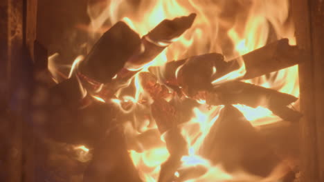 extreme close up of wood burning fiercely inside chimney. flames engulf stacked logs, emitting intense heat and vibrant orange glow with visible embers and charred textures in a dramatic fiery scene