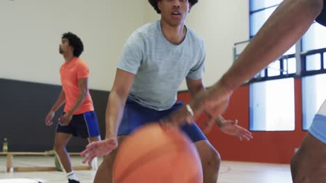 Diversos-Jugadores-Masculinos-De-Baloncesto-Driblando-Pelota-Y-Empujando-Durante-El-Juego-En-La-Cancha-Cubierta,-Cámara-Lenta