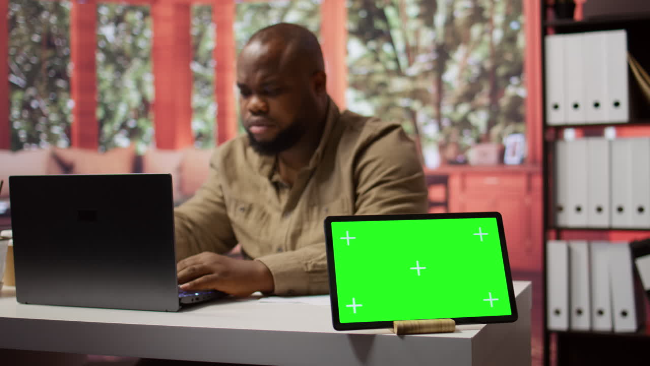 un hombre de negocios examina los informes anuales de ventas en documentos junto a una pantalla verde