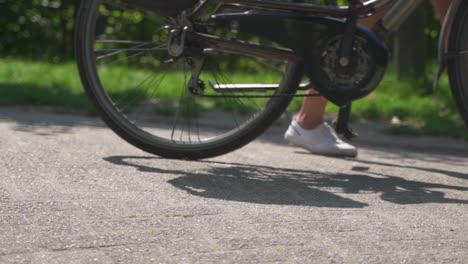 close up of a youth casually pushing his bicycle along a park road on a hot summer's day