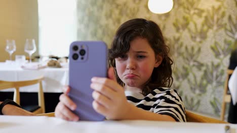 Konzentriertes-Mädchen,-Das-Sich-Im-Restaurant-Ein-Video-Auf-Dem-Smartphone-Ansieht
