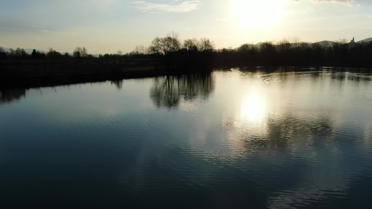 Ribnik Vrbje lake in eastern Slovenia Europe used for recreational fishing, against sun, Aerial low flyover shot