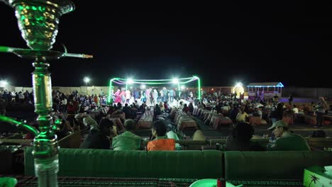 ethnic party made for tourists to see arabian culture with shisha smoking pipe in the foreground in dubai, emirates.