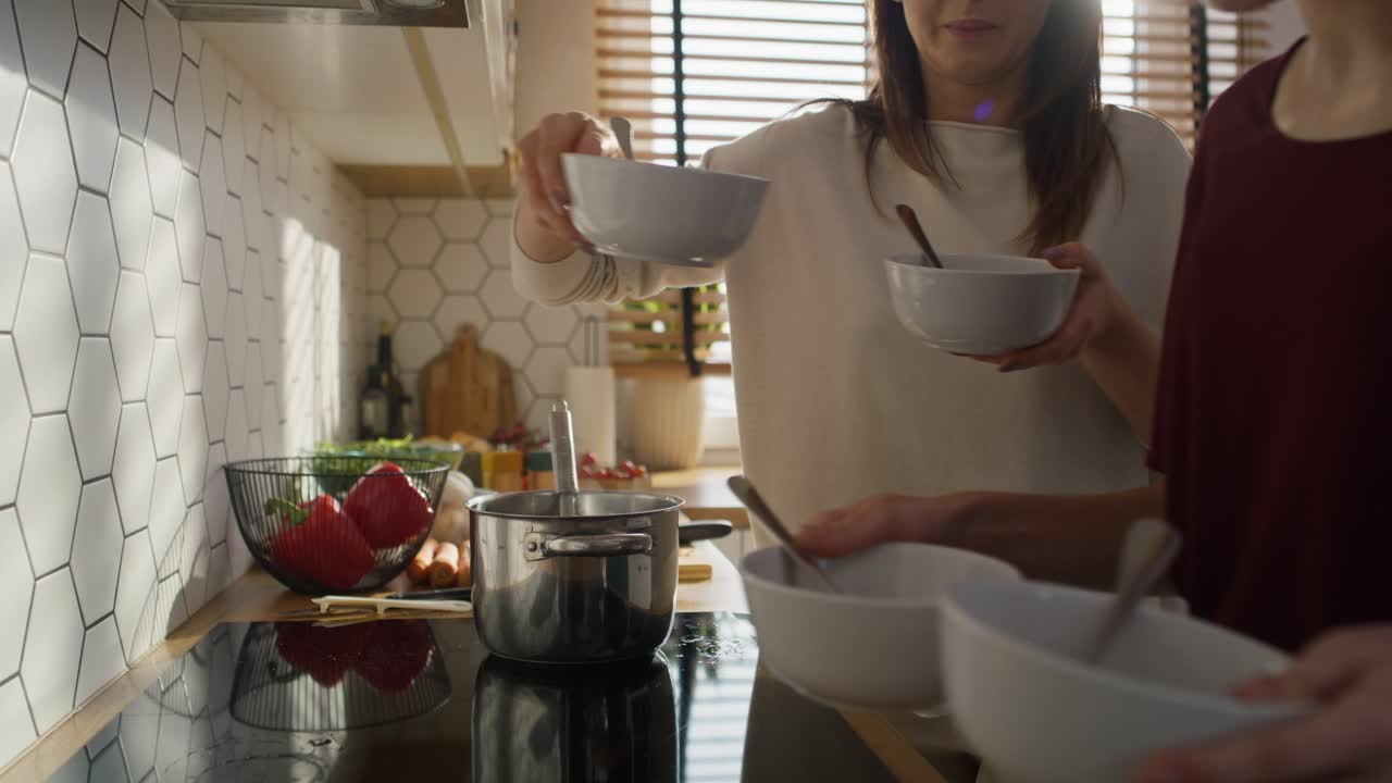 madre y hija caucásicas cocinando y sirviendo la cena juntas