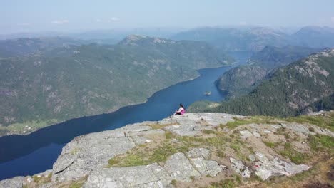 norwegian girl in the mountain, looking down at remote fjord in amazing scenery