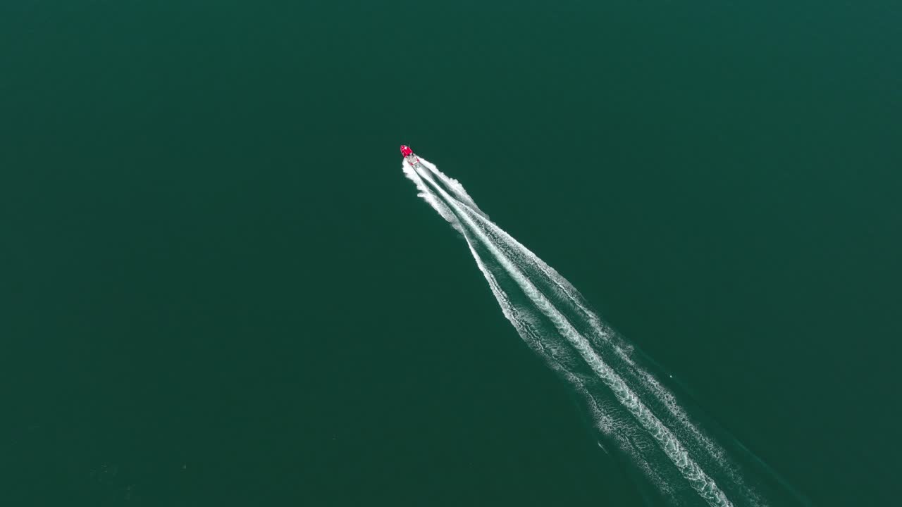 フレームを駆け抜ける赤いモーターボートの真上からの空撮。