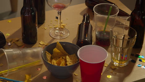 close up of messy table covered with empty wine glasses and beer bottles after house party 1