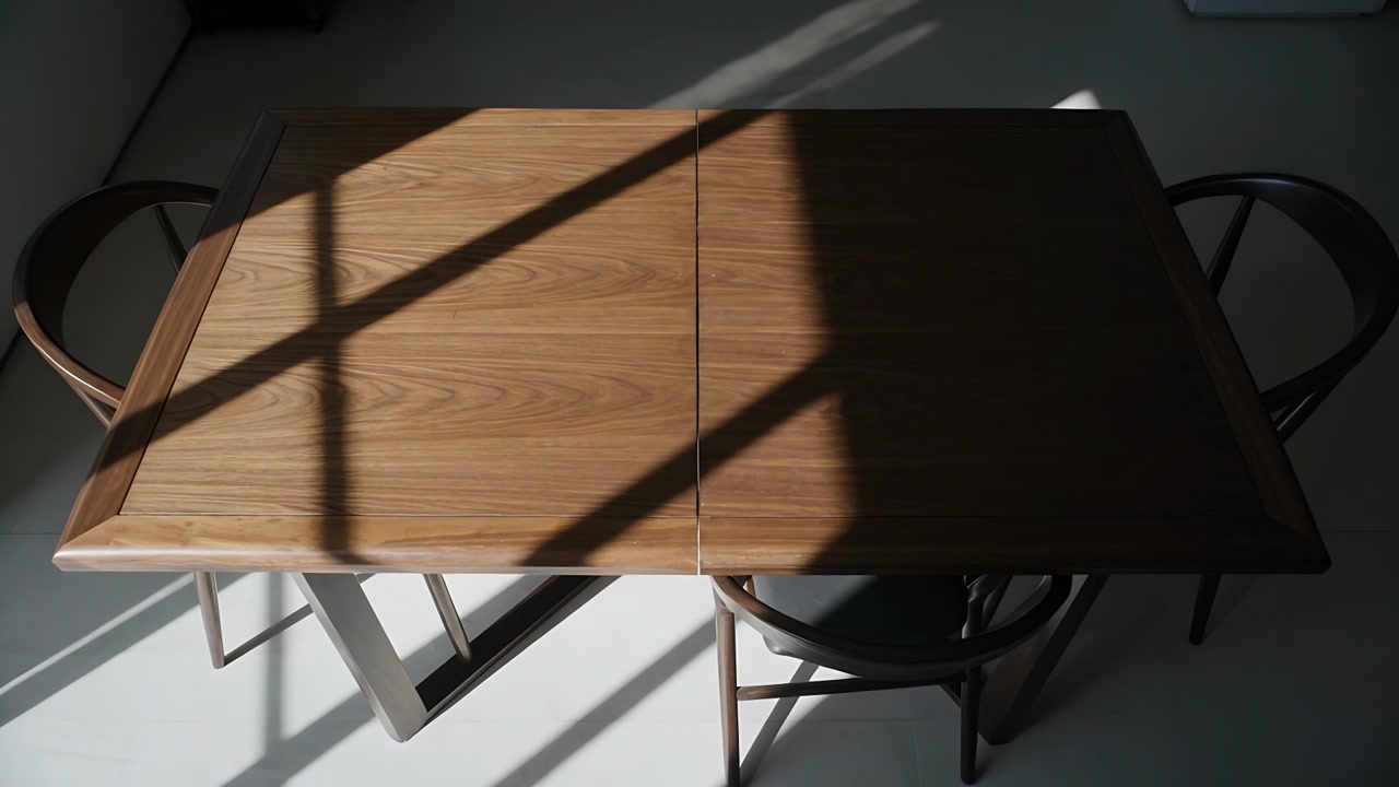 Luce solare che si sposta su un tavolo da pranzo in legno a casa, proiettando un'ombra a griglia dal sole.