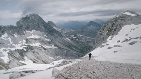 Hiker-climbing-up-on-mountain-Kanin-on-rocky-path-near-a-skiing-slope