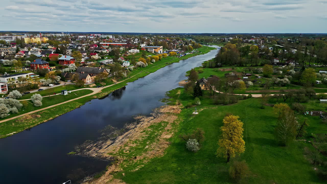 Panoramic aerial overview of calm serene river in Bauska Latvia reflecting cloudy sky