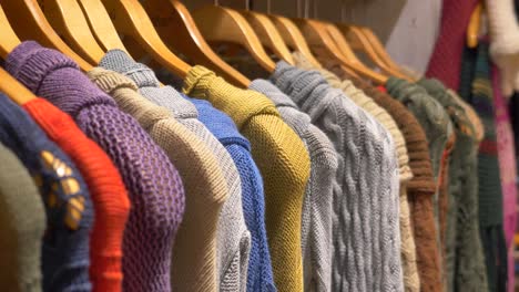 colorful knitted sweaters on hangers in a shop