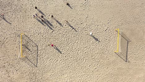 AERIAL:-Young-People-Starts-to-Play-Football-on-a-beach-in-Summer-on-Sunny-Day