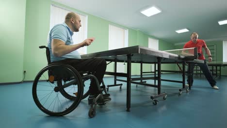 a man in a wheelchair plays ping pong. people with disabilities play table tennis. rehabilitation of the disabled. sport.