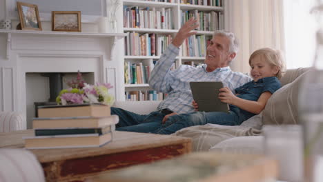 grandfather showing little boy how to use tablet computer teaching curious grandson modern technology intelligent child learning mobile device sitting with grandpa on sofa 4k