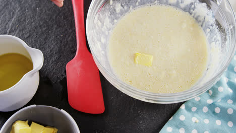 Woman-adding-butter-cubes-to-batter-in-bowl-4k