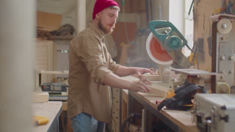 woodworker cutting plank with miter saw