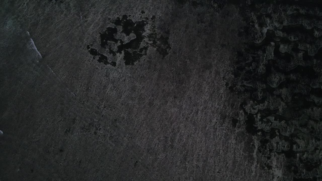 Vista Aérea de Praia Vulcânica Escura com Ondas Oceânicas Suaves
