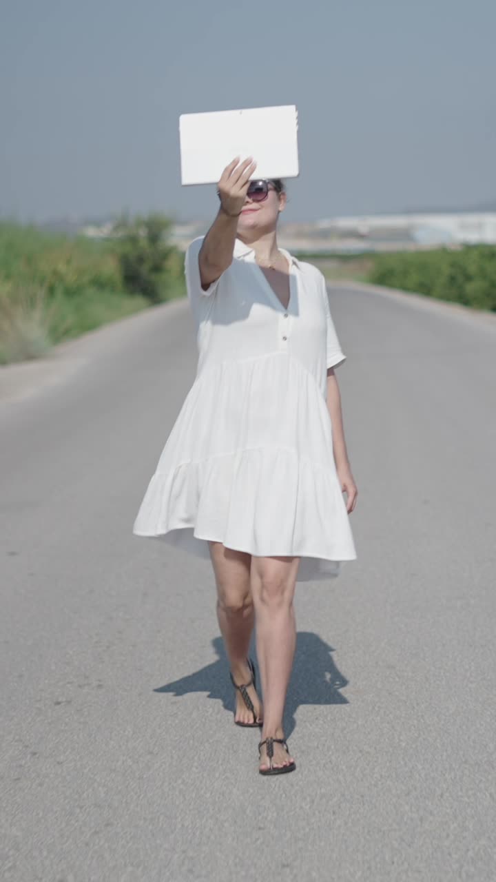 Woman in a white dress walking on a road