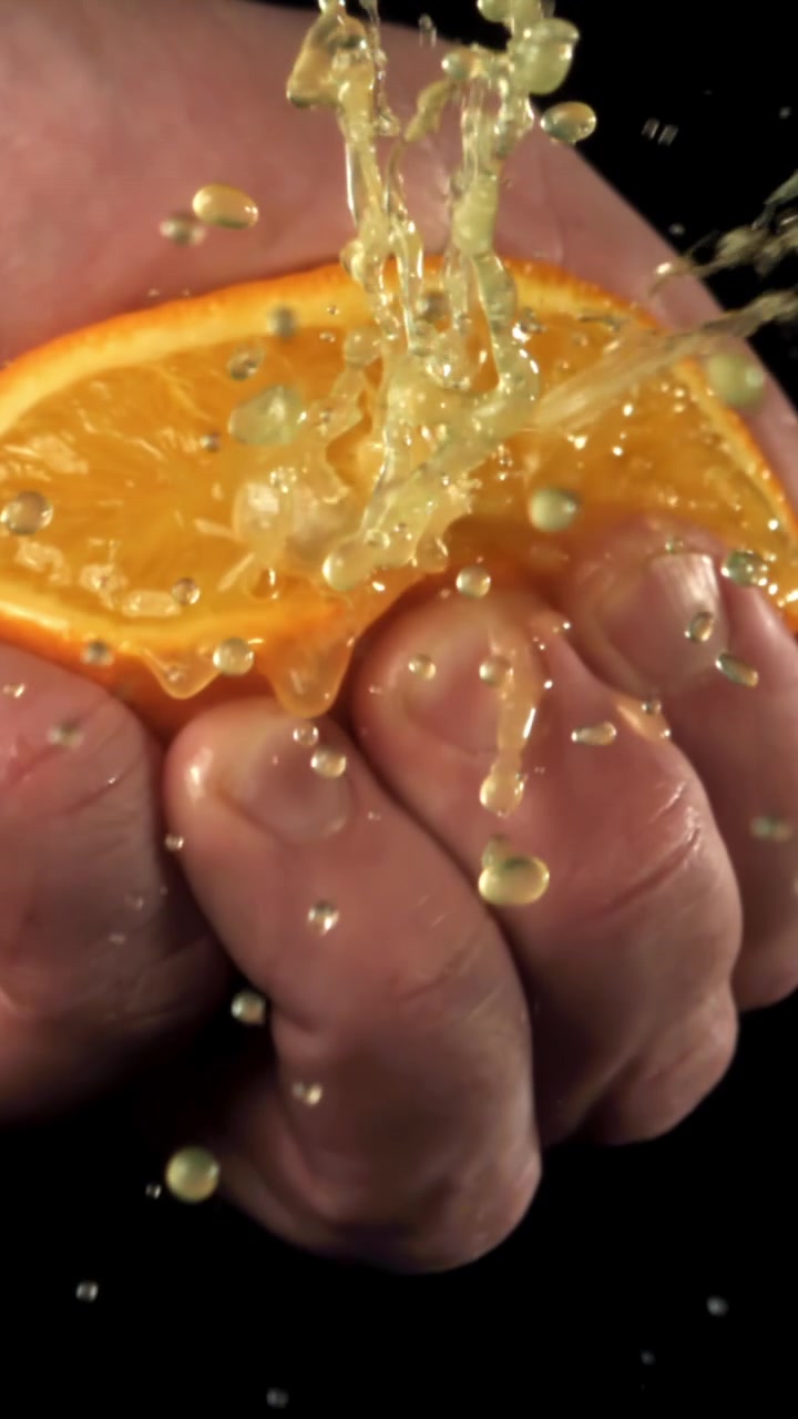 Primer plano a cámara lenta de una mano exprimiendo zumo de naranja fresco