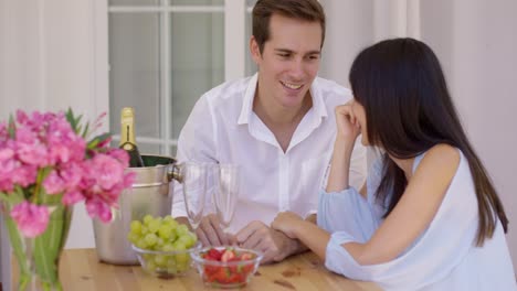 una linda pareja mixta disfrutando de vino y fruta juntos